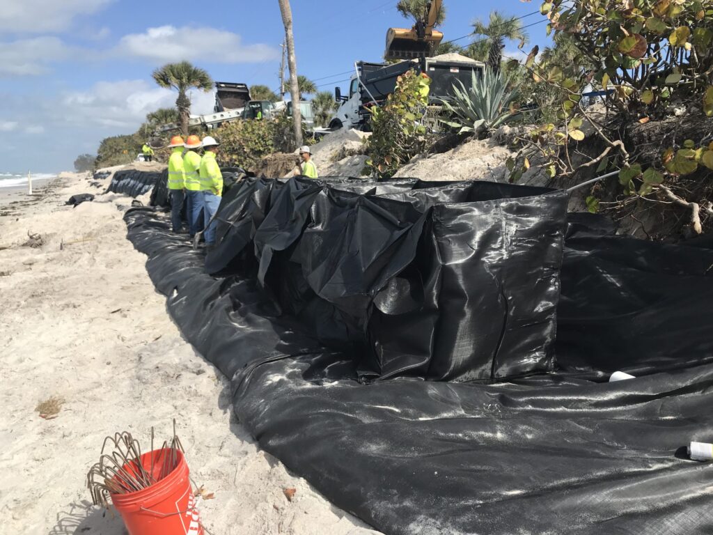 Crews assembling a coastal trapbag barrier