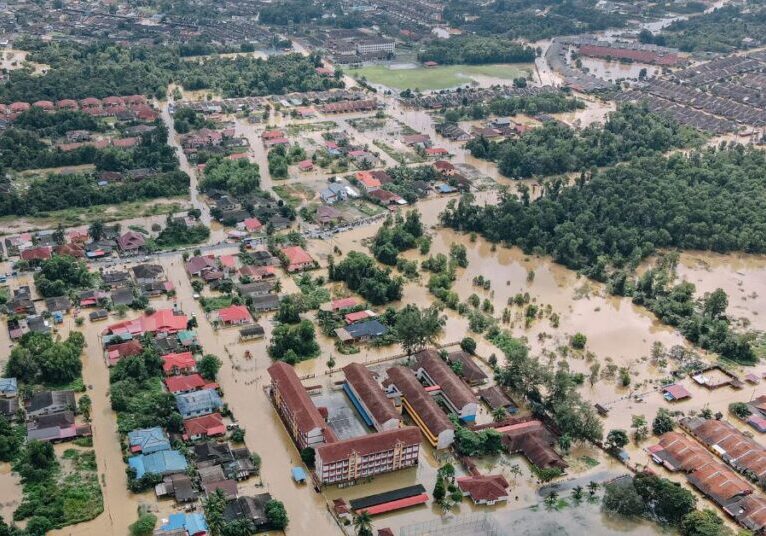 An aerial view of a town flooded by brown water.